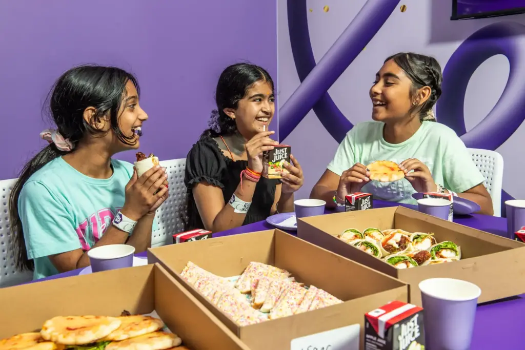 Three young girls enjoy party venue food around a table