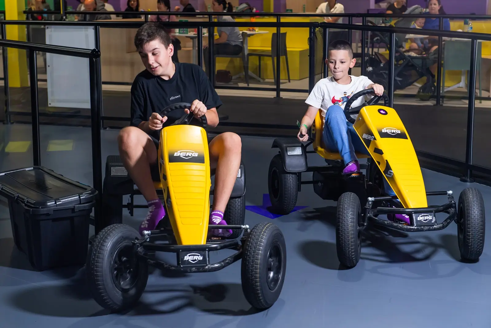 Young boys race pedal cars on indoor track