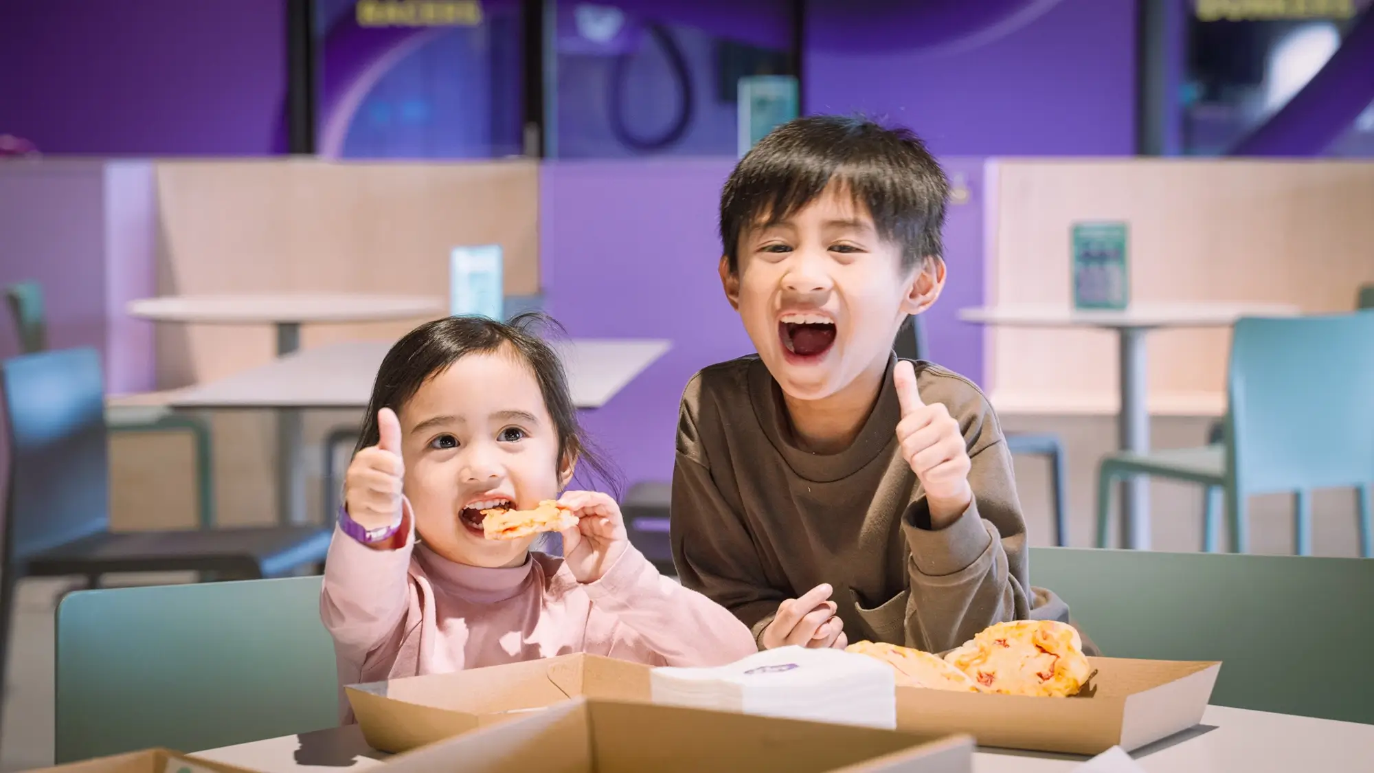 Two young children enjoying a meal at a local indoor play centre